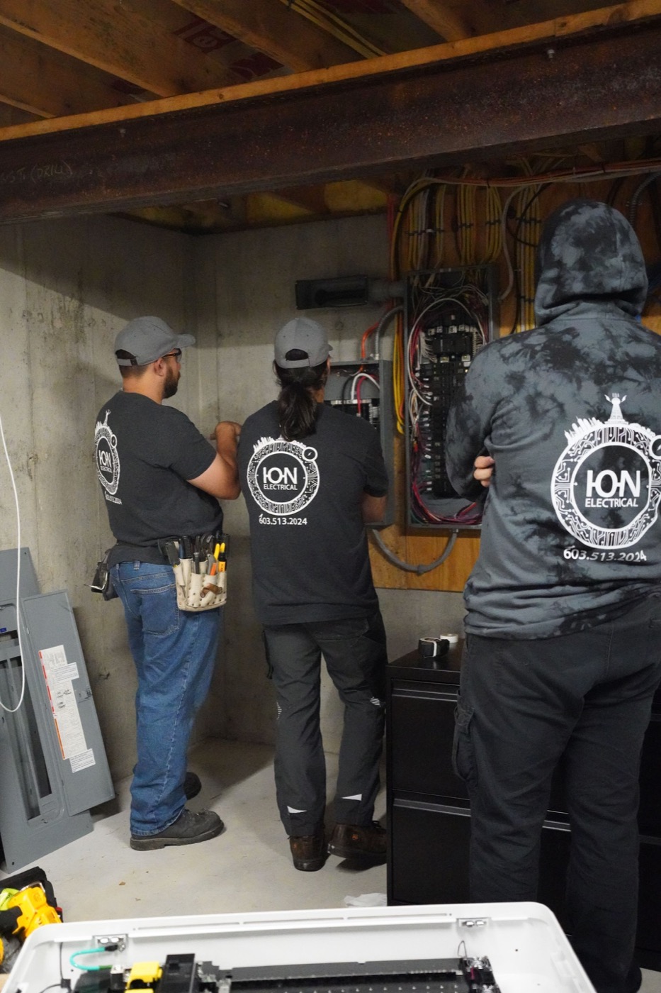Three ION Electrical team members working at an electrical panel